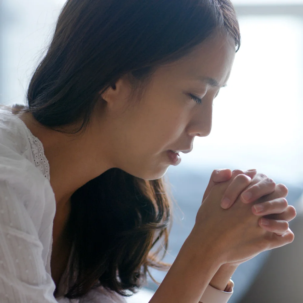 A woman praying quietly with hands folded